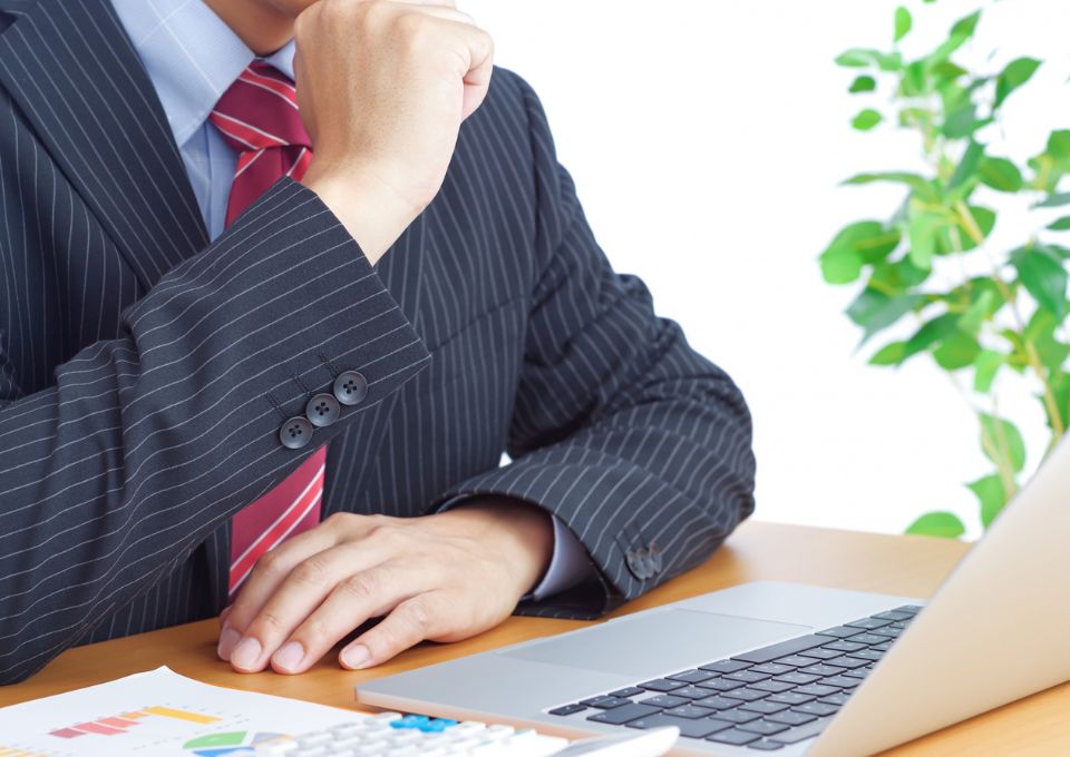 PCの前で悩む男性